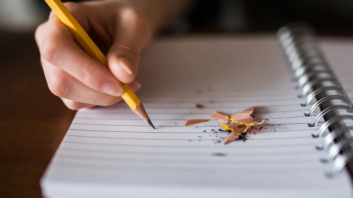 Main qui écrit au crayon dans un carnet